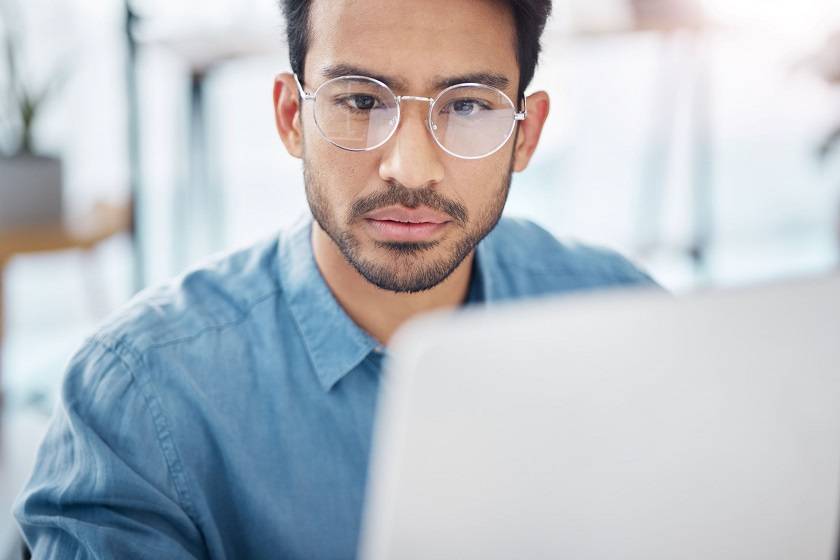 Homme avec des lunettes devant un ordinateur 