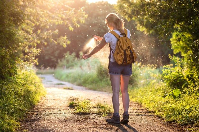 Une femme en randonnée se vaporise du spray anti-moustiques