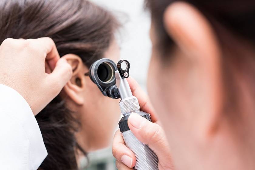 Médecin qui ausculte l'oreille d'une patiente 