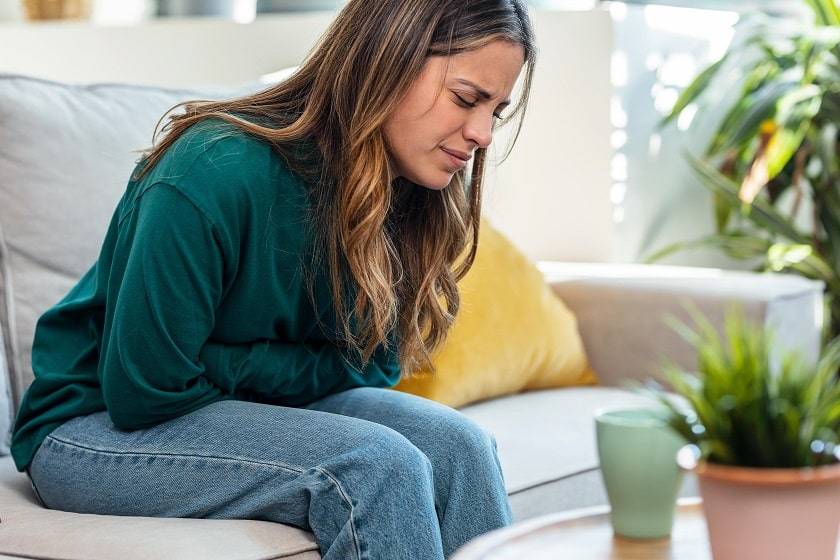 Femme se tenant le ventre assise sur un canapé