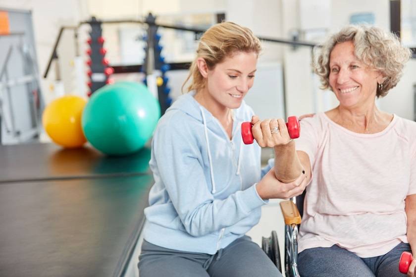 Jeune femme qui aide une femme âgée à faire du sport