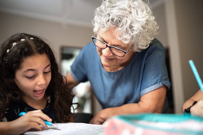 Personne âgée en train d'aider une fille avec ses devoirs