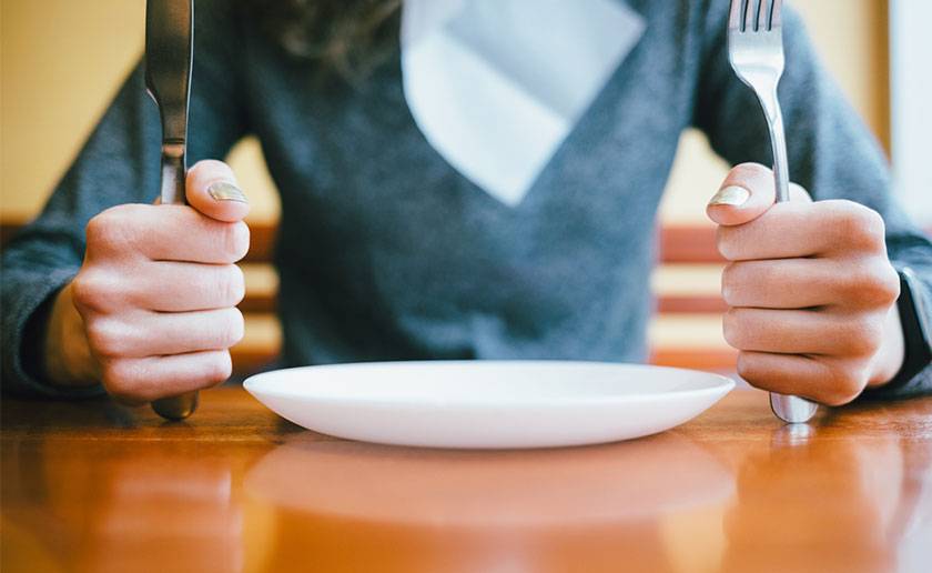 dame assise avec des couverts et une assiette