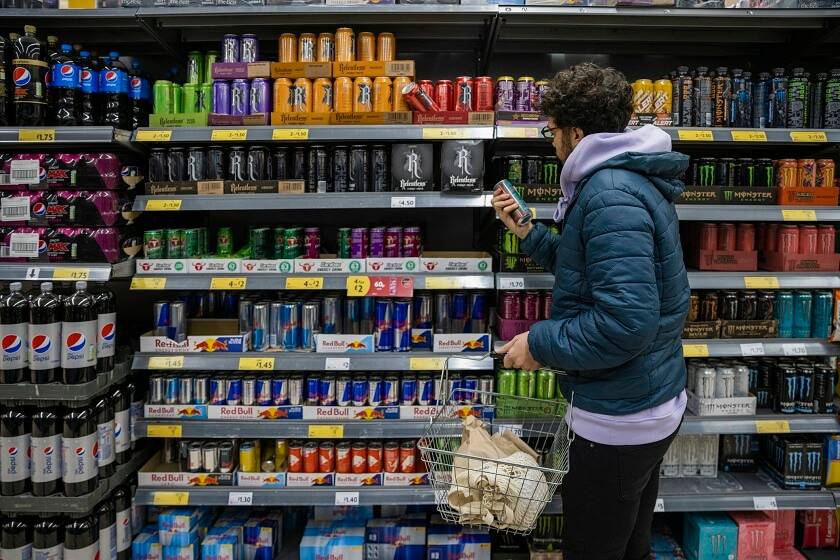 Jeune homme devant un rayon de boissons énergisantes