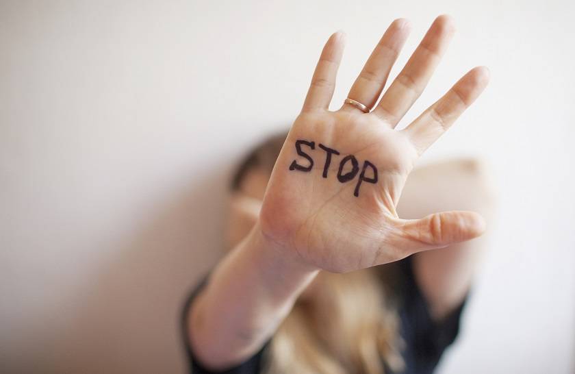 Femme apeurée qui tend sa main avec STOP écrit dessus