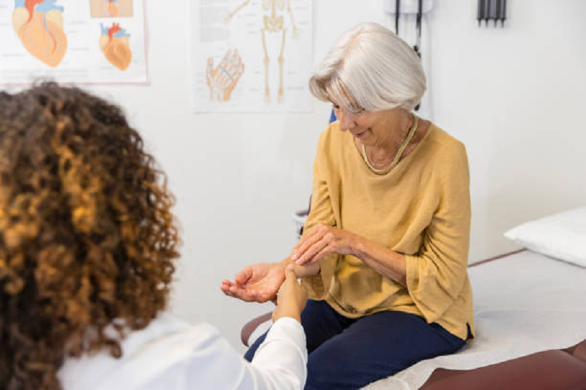 une patiente âgée décrit une douleur arthritique à une femme médecin de la main