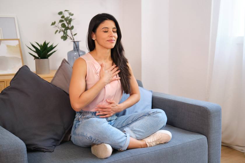 Femme assise sur un canapé avec la main sur le coeur